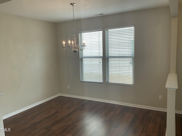 empty room with visible vents, baseboards, a notable chandelier, and dark wood-style flooring