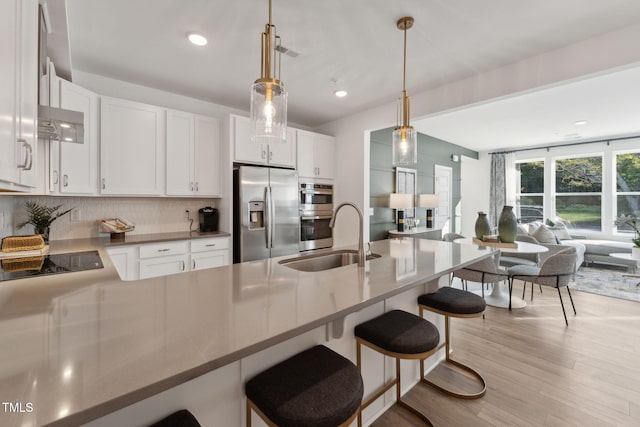 kitchen with a breakfast bar area, a sink, open floor plan, appliances with stainless steel finishes, and tasteful backsplash