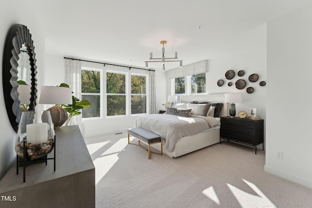 carpeted bedroom with a notable chandelier and baseboards