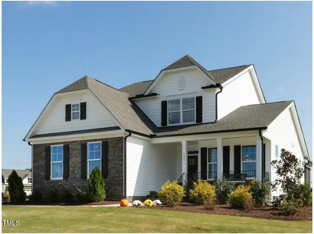 view of front of house featuring a front yard, stone siding, and a shingled roof