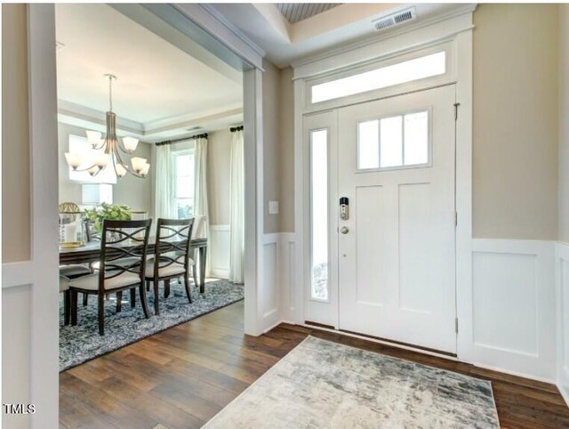 entryway with visible vents, an inviting chandelier, a wainscoted wall, and dark wood finished floors