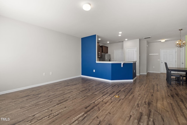 unfurnished living room featuring baseboards, visible vents, an inviting chandelier, recessed lighting, and dark wood-type flooring