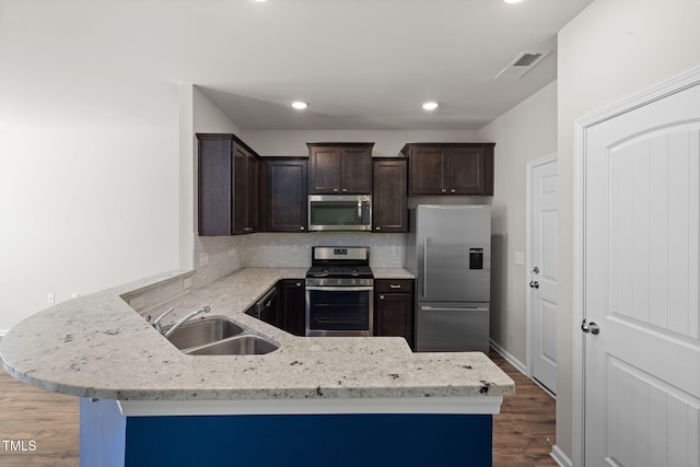 kitchen with visible vents, a sink, appliances with stainless steel finishes, a peninsula, and dark brown cabinets