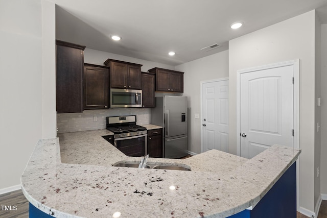 kitchen with baseboards, visible vents, stainless steel appliances, dark brown cabinetry, and tasteful backsplash