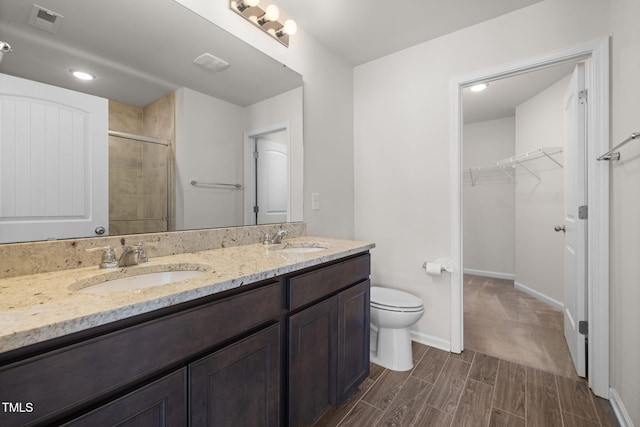 full bath with a sink, visible vents, tiled shower, and a walk in closet