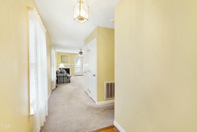 corridor featuring visible vents, baseboards, and carpet floors