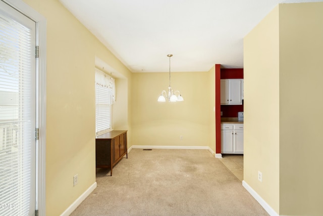 unfurnished dining area with baseboards, a chandelier, and light carpet