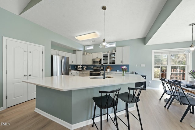 kitchen featuring light countertops, light wood-style flooring, appliances with stainless steel finishes, and a sink