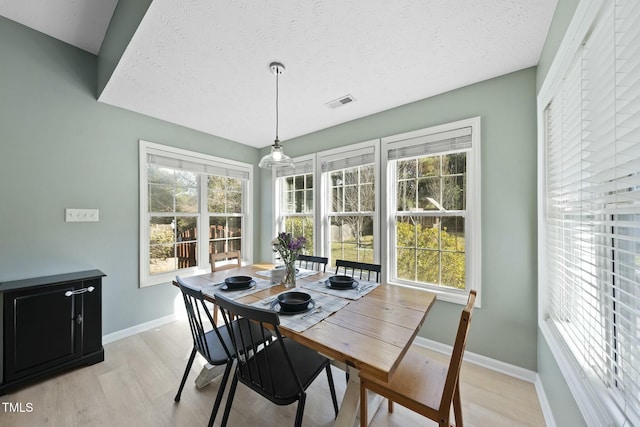 dining space with light wood finished floors, visible vents, plenty of natural light, and baseboards