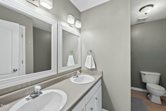 bathroom featuring visible vents, toilet, wood finished floors, and a sink