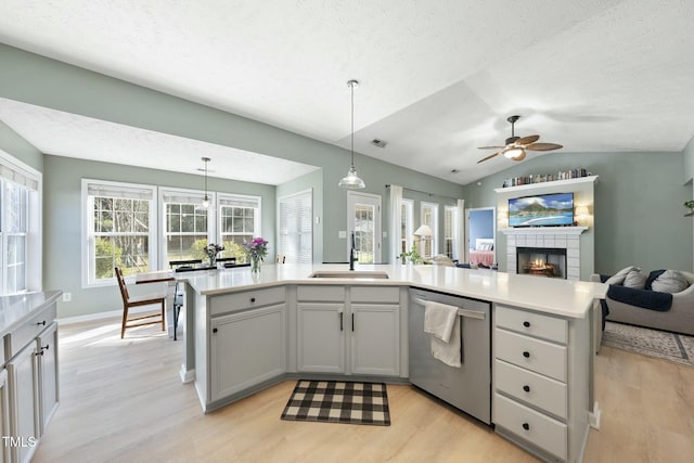 kitchen featuring a ceiling fan, a sink, open floor plan, dishwasher, and light wood-type flooring