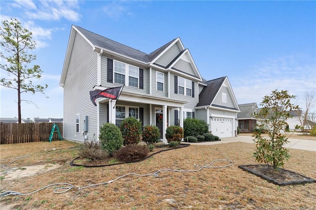 view of front facade featuring concrete driveway, an attached garage, and fence