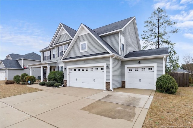 view of front of property with stone siding, driveway, and fence