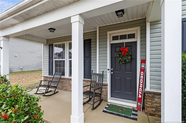 entrance to property with a porch and stone siding