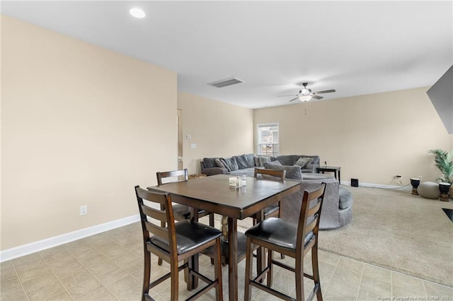 dining room with light carpet, visible vents, baseboards, and ceiling fan