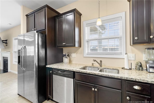 kitchen featuring dark brown cabinets, light stone countertops, appliances with stainless steel finishes, and a sink