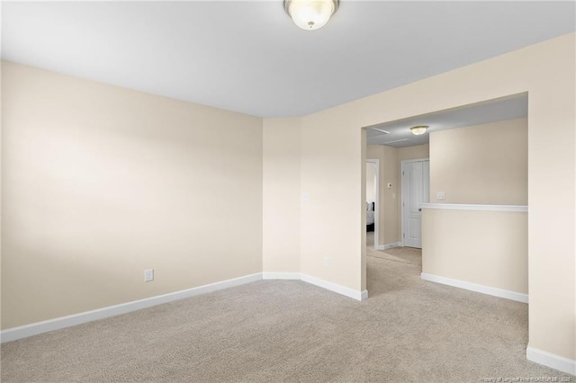 empty room featuring light colored carpet and baseboards