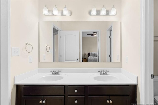 ensuite bathroom with double vanity, connected bathroom, and a sink