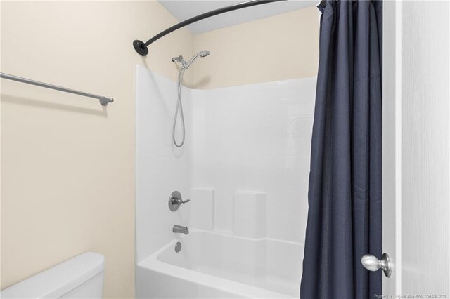 full bathroom featuring shower / bath combination with curtain and toilet