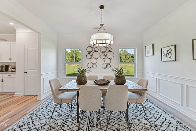 dining room featuring a wealth of natural light, ornamental molding, and light wood finished floors