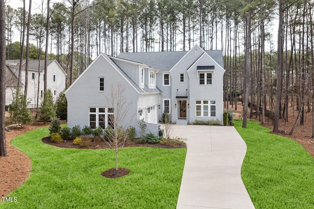 modern farmhouse with a garage, concrete driveway, a front yard, and a shingled roof