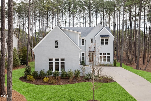 view of front facade with a front yard, board and batten siding, and driveway