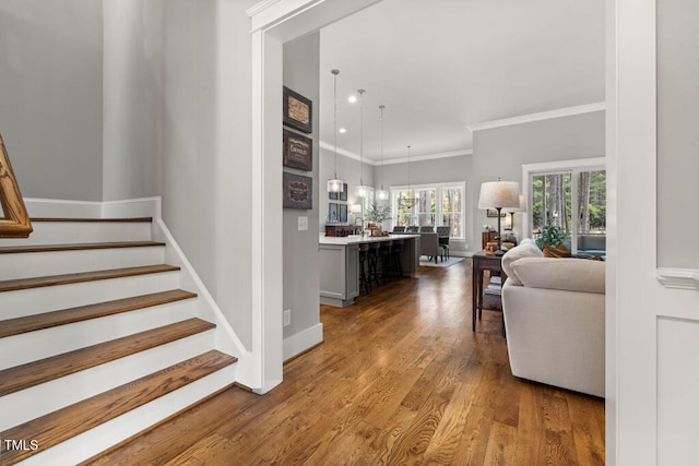 interior space featuring recessed lighting, baseboards, wood finished floors, and crown molding