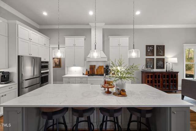 kitchen featuring a breakfast bar area, ornamental molding, a large island, white cabinets, and appliances with stainless steel finishes