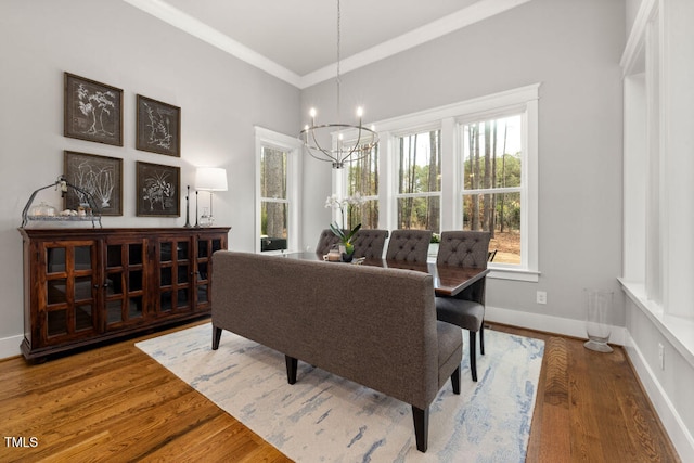 dining area featuring baseboards, crown molding, an inviting chandelier, and wood finished floors