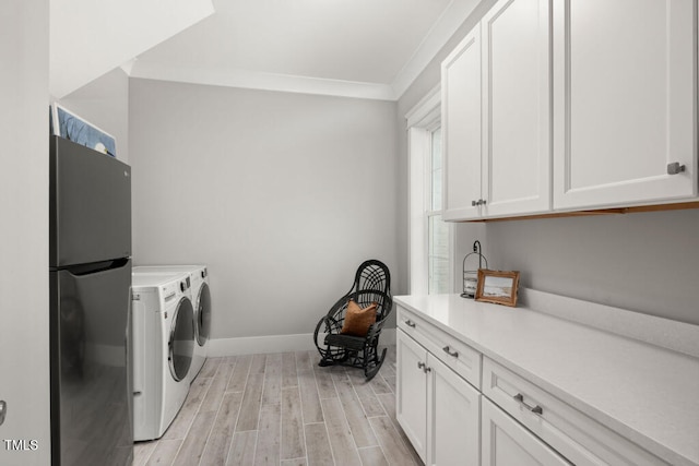 washroom with wood finish floors, ornamental molding, washer and clothes dryer, cabinet space, and baseboards