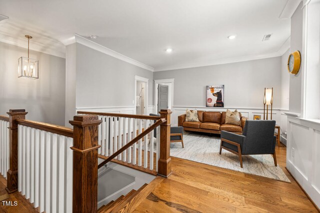 interior space featuring a wainscoted wall, wood finished floors, visible vents, and ornamental molding