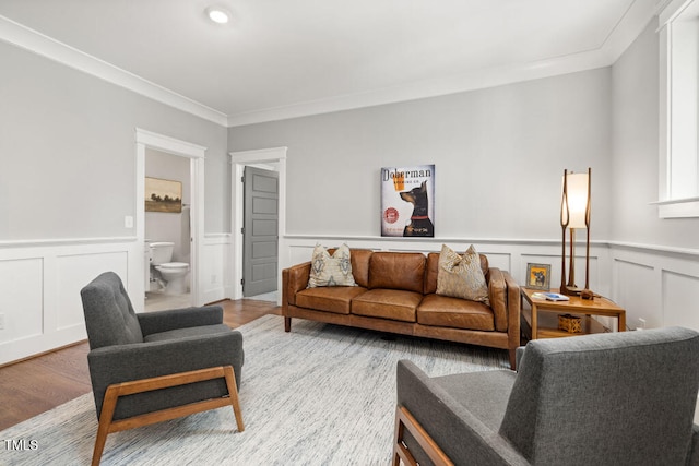 living area with a wainscoted wall, crown molding, and wood finished floors