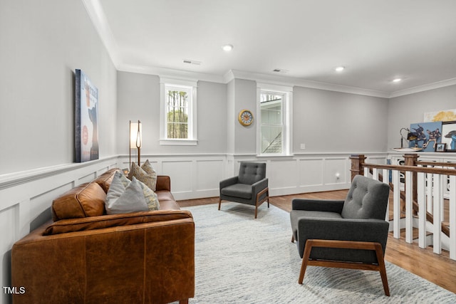 living room with wood finished floors, visible vents, recessed lighting, ornamental molding, and wainscoting