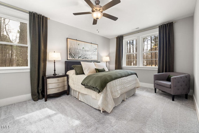 carpeted bedroom featuring baseboards, multiple windows, and a ceiling fan