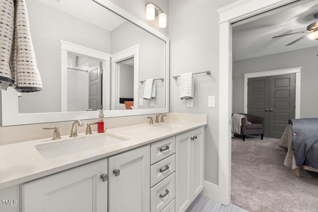 ensuite bathroom featuring double vanity, ensuite bath, a ceiling fan, and a sink