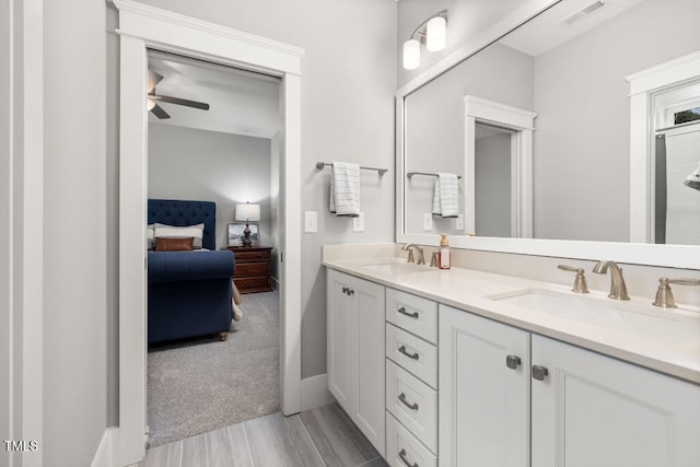 ensuite bathroom with double vanity, a ceiling fan, visible vents, and a sink