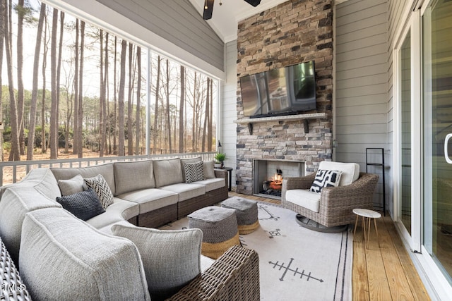 interior space featuring wooden walls, ceiling fan, lofted ceiling, an outdoor stone fireplace, and wood-type flooring