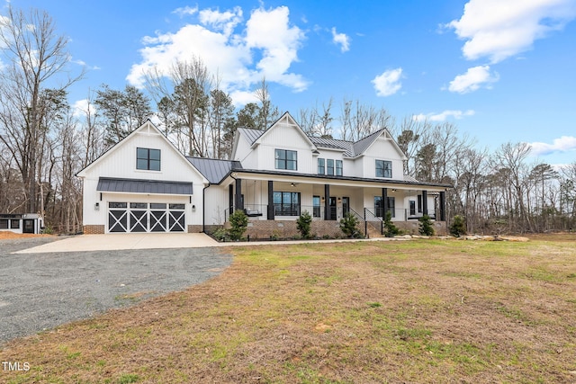 modern inspired farmhouse featuring driveway, a standing seam roof, covered porch, an attached garage, and metal roof