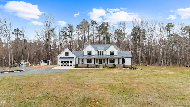 view of front facade with a garage, driveway, metal roof, and a front yard