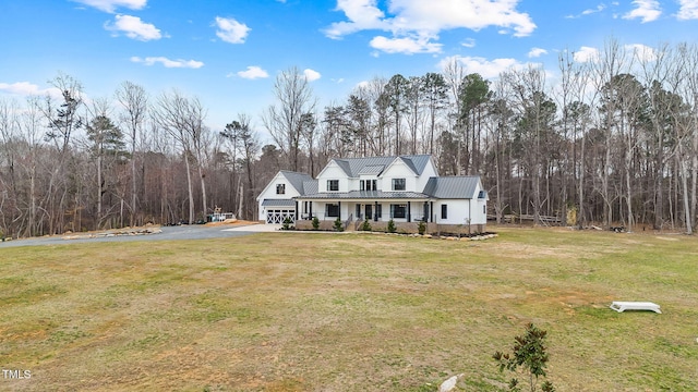 view of front of home with a front yard, a porch, an attached garage, aphalt driveway, and metal roof