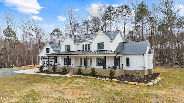 modern inspired farmhouse featuring metal roof, covered porch, a front yard, and a standing seam roof