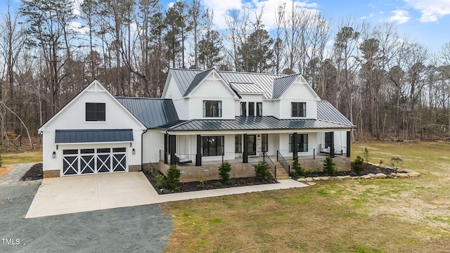 modern farmhouse style home featuring a front yard, covered porch, metal roof, driveway, and a standing seam roof