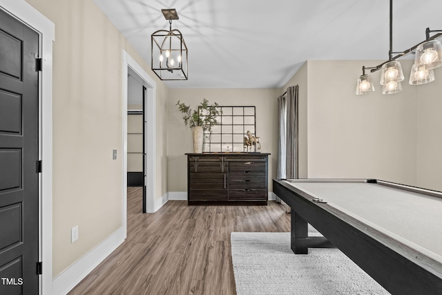 recreation room with a chandelier, baseboards, and wood finished floors