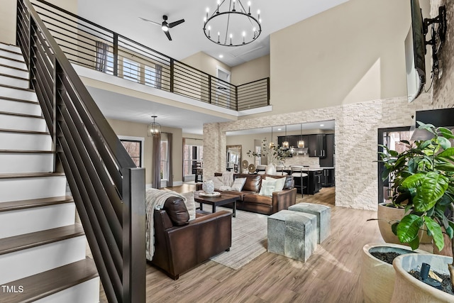 living room featuring light wood finished floors, stairs, an inviting chandelier, and a towering ceiling