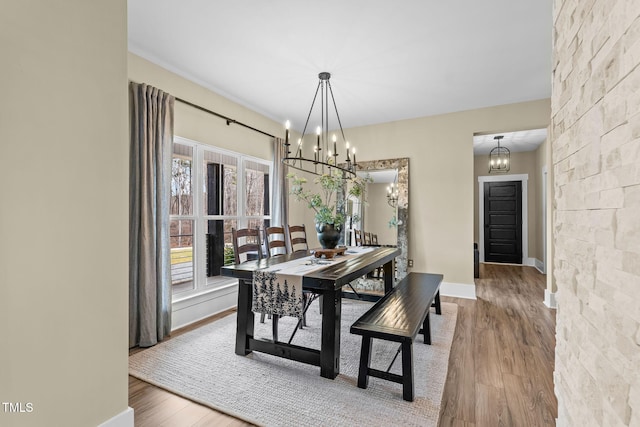 dining space featuring an inviting chandelier, wood finished floors, and baseboards