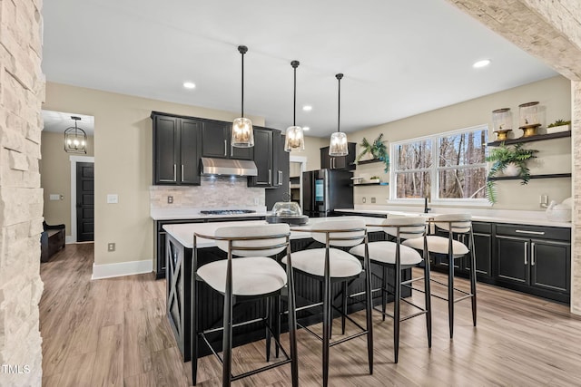 kitchen featuring under cabinet range hood, decorative backsplash, smart refrigerator, light wood-style floors, and open shelves