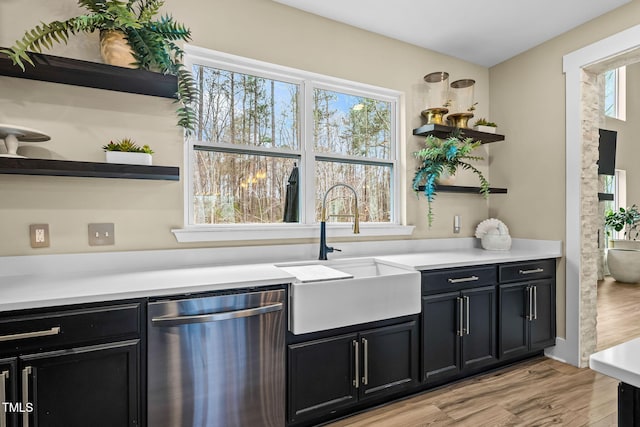 kitchen featuring open shelves, stainless steel dishwasher, dark cabinetry, and a sink