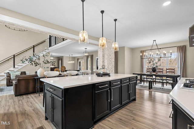 kitchen featuring light wood finished floors, light countertops, dark cabinetry, and an inviting chandelier