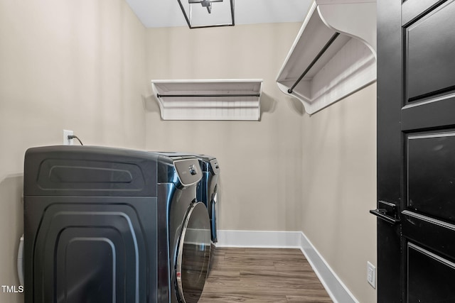 laundry room featuring laundry area, wood finished floors, baseboards, and washing machine and clothes dryer