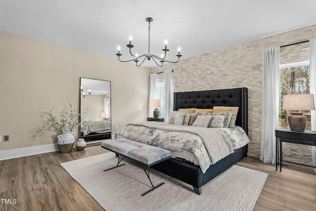 bedroom featuring a chandelier, multiple windows, baseboards, and wood finished floors